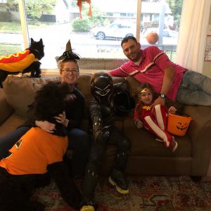 Erin Oxender posing on couch with family in Halloween costumes.