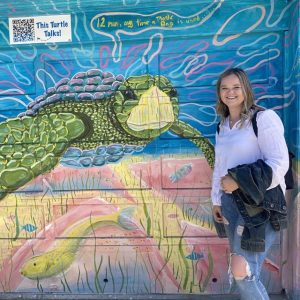 Courtney Weber posting in front of a sea turtle mural