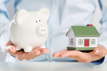man holding piggy bank and a house.