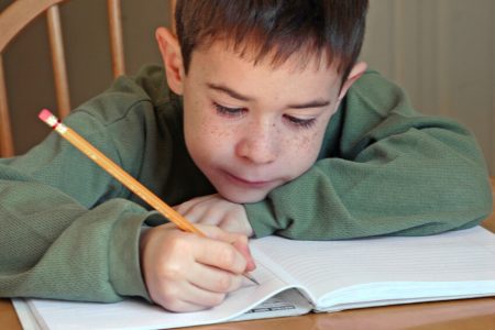 Boy writing in notebook.